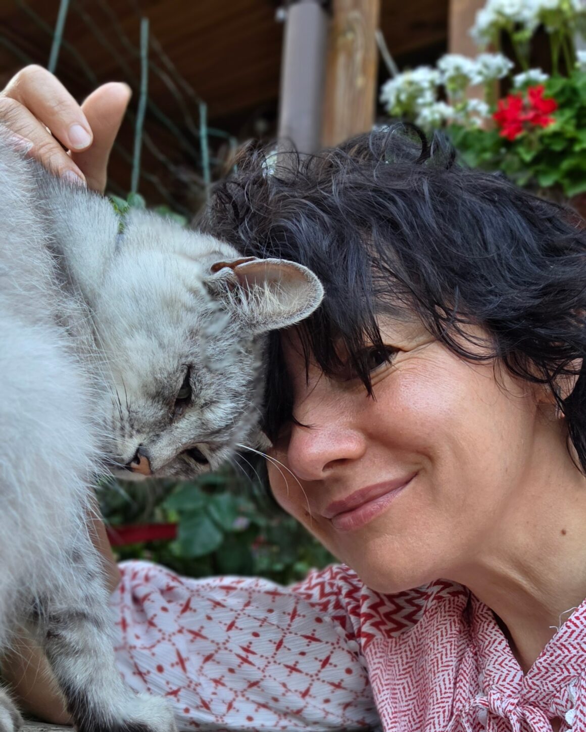 Любов, засновниця KvitkoDar, зі своїм котом Ілоном на фоні квітучої веранди